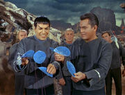 Spock smiling as he grasps blue flowers