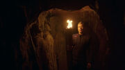 Tucker with torch in catacombs