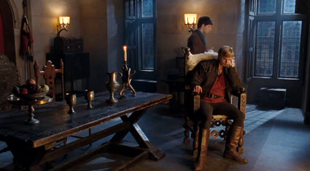 Arthur sits in a chair while Merlin paces.