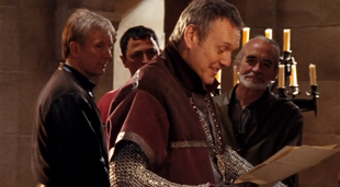 Uther laughs over some parchment with his advisors