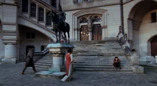 Merlin sits on the steps in the Square. Guinevere approaches