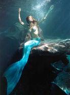 Erika Heynatz (Diana) sitting on a reef.