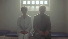 Hilary and Richard sitting in a prison cell