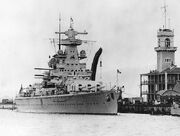 Black-and-white photograph of heavy cruiser Admiral Scheer moored at dock.