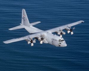 Straight-wing, four-engine turboprop-driven aircraft overflying water