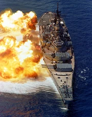 The firepower of a battleship demonstrated by  (ca. 1984). The muzzle blast distorts the ocean surface.