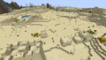 A deeply buried desert pyramid outside of a village. In the distance, a pillager tower and another pyramid spawned.