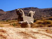 La foto muestra una escultura con dos cabezas de rapaces pegadas espalda a espalda y patas anteriores de león.