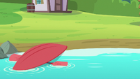 Red overturned kayak floating in the water S7E21