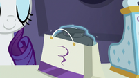 Rarity placing folded shirt in a bag S8E4