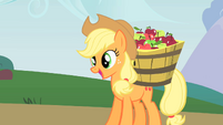 Applejack cheerfully carrying a bucket of apples.