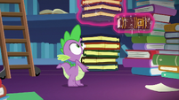 Twilight levitates a book out of Spike's stack S7E26