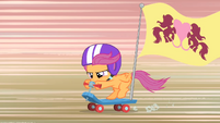 Scootaloo riding the scooter with a flag.