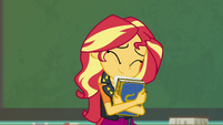 Sunset Shimmer smiling and hugging a yearbook EGFF