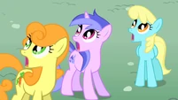 Scootaloo takes to the air with her scooter; Golden Harvest, Sea Swirl and Sassaflash watch in awe.