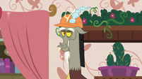 Bookshelf and flowers appear behind Discord S7E12