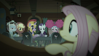 Fluttershy looks at her friends from behind couch S5E21