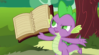 Spike holds up book with torn out page S03E10