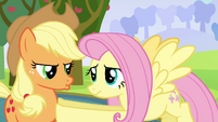 Applejack getting pouty while Fluttershy holds her back