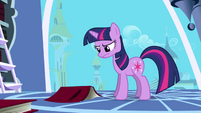 Twilight frowning at a book on the floor S1E01