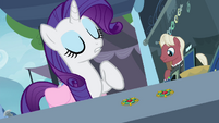 Rarity pointing at one of the brooches S4E22