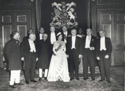 A formal group of Elizabeth in tiara and evening dress with eleven politicians in evening dress or national costume