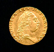 Gold coin bearing the profile of a round-headed George wearing a classical Roman-style haircut and a laurel wreath.