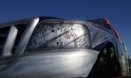 A close-up of Hurricane Force's headlights at Monster Jam World Finals XVII, featuring playing cards and a flame pattern.