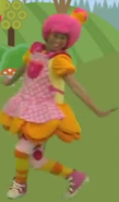 In Farmer in the Dell, she wears a pink apron with white polka dots and a hot pink pocket on it