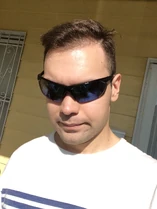 Ethan half-smiling, and wearing sunglasses instead of his usual glasses, his “patriotic look” hairstyle, and a white T-shirt with blue horizontal stripes in the center.