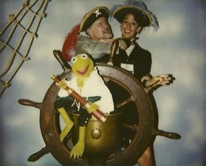 Roberts menaces Muppet Workshop coordinator Valerie Simon behind an unsuspecting  at the Muppet Treasure Island wrap party.