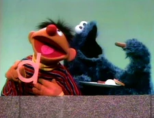 Cookie Monster eats two hot dogs and a doughnut while Ernie sings "Dee, Dee, Dee."