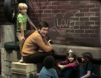 Bob and the kids sit in the yard and write "love" on the wall of 123 Sesame Street in Episode 0147
