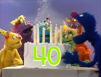 Grover blows out the birthday cake candles in a Monsterpiece Theater sketch