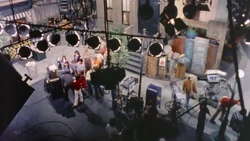 The cast and crew watch a playback after taping a scene.