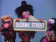 The character with other Anything Muppet hippies holding up the Sesame Street sign.
