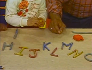 A kid wearing a Strawberry Shortcake shirt on Sesame Street.
