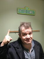 Oswalt pointing under his own personalized Sesame Street sign.