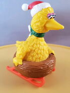 Big Bird wearing a santa hat, in his nest on sleigh runners