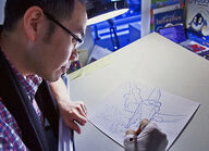 Evan Cheng drawing a sketch for the comic strip.