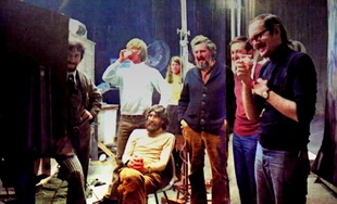 Performers and crew watch a playback. In foreground, from left to right: Caroll Spinney, Daniel Seagren, Jim Henson (seated), Jon Stone, Bob McGrath, and Frank Oz