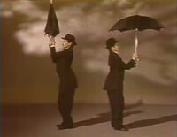 Maria as Charlie Chaplin and his look-a-like each have an umbrella. (First: Episode 1174)