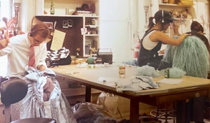 Behind the scenes at :  works on Prairie's dress while another builder assembles Mona.