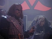 Michael Dorn and Robert O'Reilly as  and  in an episode of , sporting Fletcher's costumes. Worf holds a knife known as a ;'"`UNIQ--ref-0000000D-QINU`"' behind the actors is the bottom half of the Klingon emblem.