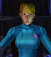 A computer-generated image of a woman wearing a tight-fitting blue suit. She has blond hair and green eyes, and appears to be sitting in a chair.