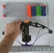 The Hawkeye Longshot Bow compared to an eighteen dart clip and an adult hand.