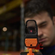A model aiming down a Red Dot Sight.