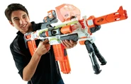 A model aiming the Modulus, notably equipped with a Flip Clip, a Blast Shield, a Red Dot Sight, a Long Range Barrel, and a Folding Bi-Pod.