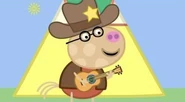 Pedro Pony holding a guitar and dressed up as a cowboy.