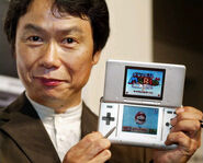 Miyamoto holding the original Nintendo DS, playing Super Mario 64 DS.